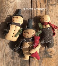 three snowmen made out of clay sitting on top of a wooden table with the words snow