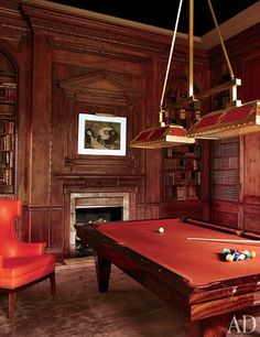 a pool table and chairs in a room with wood paneled walls, an old fireplace and chandelier