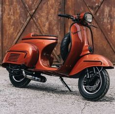 an orange scooter parked in front of a wooden door