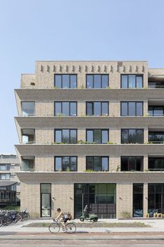 an apartment building with many windows and bicycles parked on the street in front of it