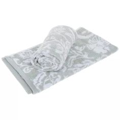 a white and grey towel folded up on top of a white tablecloth with an ornate pattern