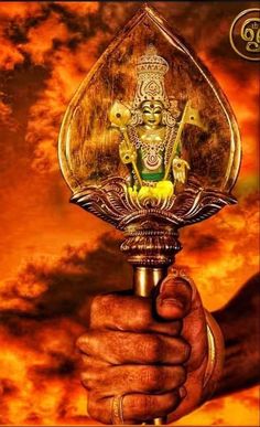 a person holding a metal object in their hand with an image of lord ganesha on it