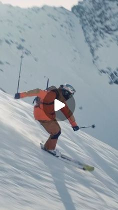 a man riding skis down the side of a snow covered slope in front of a mountain