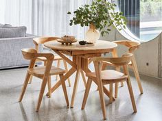 a wooden table with four chairs and a potted plant in the middle on top