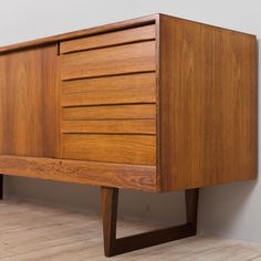 a wooden dresser sitting on top of a hard wood floor next to a white wall