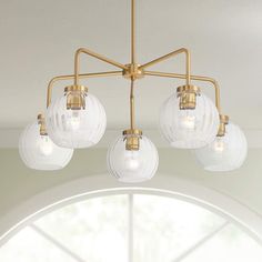 a chandelier with five clear glass globes hanging from it's brass frame