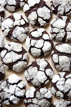 chocolate crinkle cookies covered in powdered sugar on a sheet of parchment paper