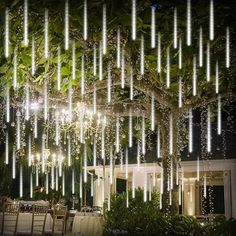 an outdoor dining area with lights hanging from the ceiling and table set up under a tree