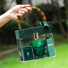 a hand holding a green bag with some items inside it and the handle is made out of bamboo