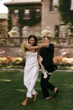 a man and woman are running in the grass with their arms around each other as they hold hands