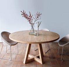 a wooden table with two chairs and a vase filled with flowers sitting on top of it