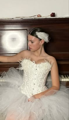 a woman in a white dress sitting next to a piano with her hand on the keys