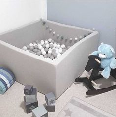 a blue teddy bear sitting on a rocking toy in a room with balls and toys