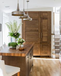 a kitchen with wooden floors and cabinets in the background is a dining room table that has chairs around it