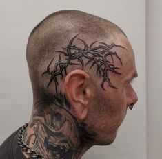 a man with tattoos on his head and neck is looking into the distance while wearing a chain around his neck