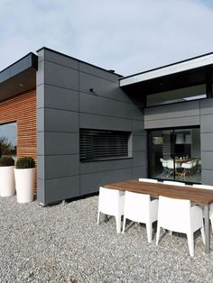 an outdoor dining area with table, chairs and potted plants in front of the house