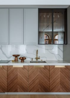 a kitchen with marble counter tops and wooden cabinetry, along with brass faucets