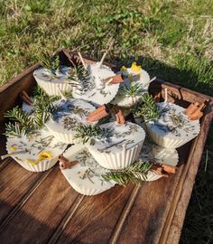 some cupcakes are sitting on a wooden tray with flowers and sticks sticking out of them