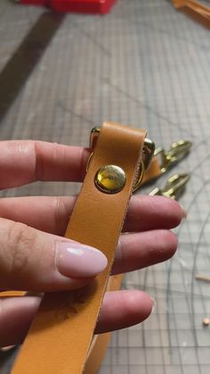 a hand holding a brown leather case with gold hardware