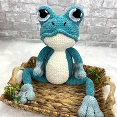 a crocheted frog sitting in a basket