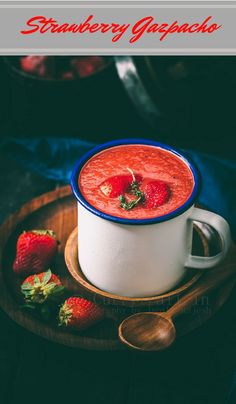 there is a bowl of soup with strawberries on the side