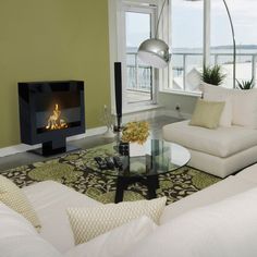 a living room filled with furniture and a fire place next to a large window overlooking the ocean