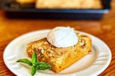 a piece of cake on a white plate with whipped cream and mint sprig