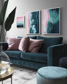 a living room with blue couches and paintings on the wall above them, along with a round coffee table