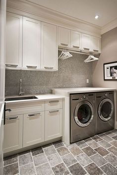 a washer and dryer in a small room with white cabinets on the walls