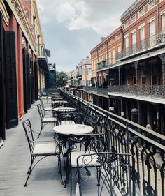 tables and chairs are lined up on the side of an alleyway with buildings in the background