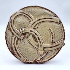 a white and brown ceramic plate with designs on the front, sitting on a white surface