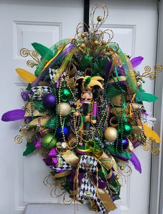 a wreath is hanging on the front door decorated with mardi gras decorations and beads