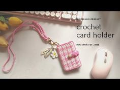 a pink crochet card holder next to a computer mouse