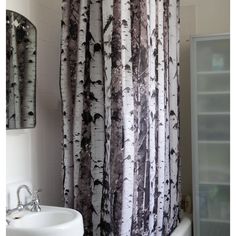 a shower curtain with black and white trees printed on it in a bathroom next to a sink