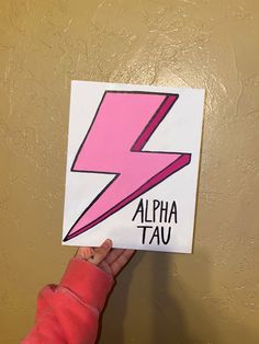 a person holding up a sign with a pink lightning bolt on it's side