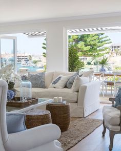 a living room filled with white furniture and lots of windows overlooking the water at night