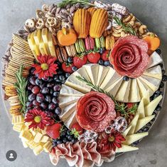 a platter filled with cheeses, fruits and flowers on top of a table