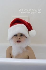 a baby in a bathtub wearing a santa hat