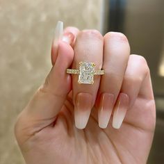 a woman's hand holding a yellow and white diamond ring