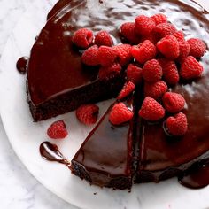 a chocolate cake topped with raspberries on a white plate