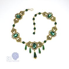 "Noble elegance is conveyed in the richly textured Marquise Xanthe necklace. Smooth glass teardrops capped in filigree dangle sumptuously at the front of this link style necklace while emerald green gems and antique gold swirled links envelop the neck. This necklace closes with a hook clasp and the length is adjustable from 16\" to 20\" to be worn at the length of your choice. Coordinating earrings are also available to complete the set. Also available in black onyx, sapphire blue, ruby red, and Green Emerald Jeweled Necklace, Green Jeweled Emerald Necklace, Emerald Teardrop Pendant Necklace For Weddings, Elegant Beaded Emerald Necklaces, Elegant Beaded Emerald Necklace, Emerald Jeweled Necklaces As Gifts, Emerald Jeweled Necklaces For Gifts, Emerald Jeweled Necklace For Gift, Elegant Green Necklace With Bead Caps