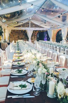 a long table is set up for an event with white linens and greenery