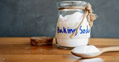 a glass jar filled with baking soda next to a wooden spoon