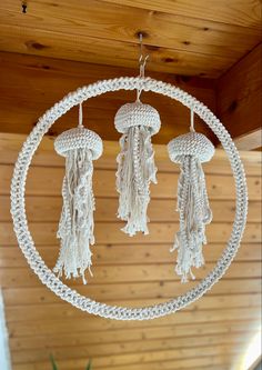 three white crocheted objects hanging from a circular ceiling fixture with tassels