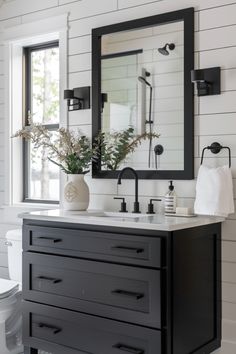 a black and white bathroom with a large mirror above the vanity, toilet and sink