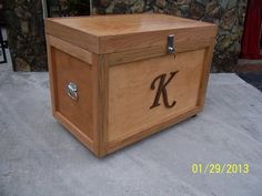 a large wooden box with the letter k on it's lid is sitting in front of a house