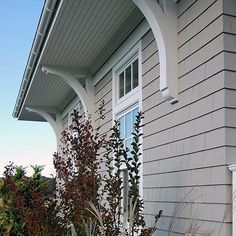 a fire hydrant sitting on the side of a house next to a planter