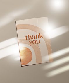 a thank you card hanging from the ceiling with sunlight coming in through the window behind it