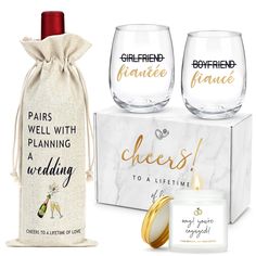 two wine glasses and a candle are sitting next to each other in front of a gift bag