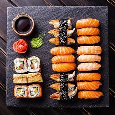 sushi on a slate platter with chopsticks and sauce